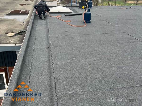 Dakdekker repareert bitumen dakbedekking op groot plat dak in Vianen