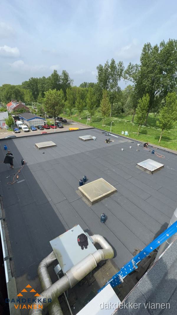 Dakdekker aan het werk op groot plat dak met bitumen in Vianen