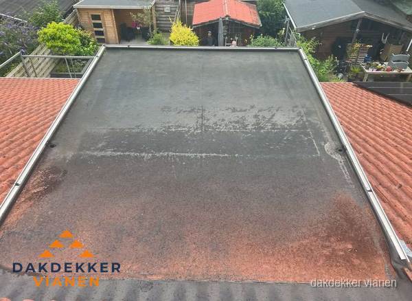 Verouderd plat dak met slijtage tussen schuine daken in Vianen