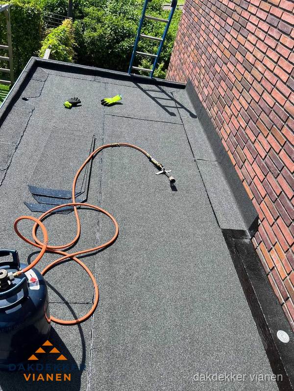 Plat dak met bitumen en brandgereedschap van dakdekkersbedrijf in Vianen