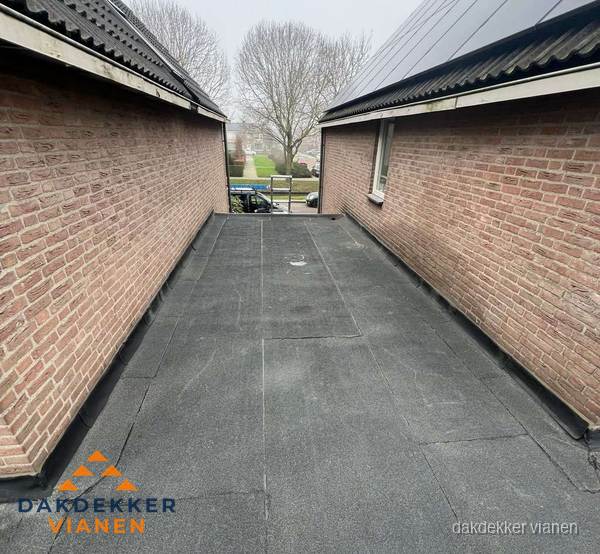 Plat dak met bitumen dakbedekking tussen bakstenen muren in Vianen